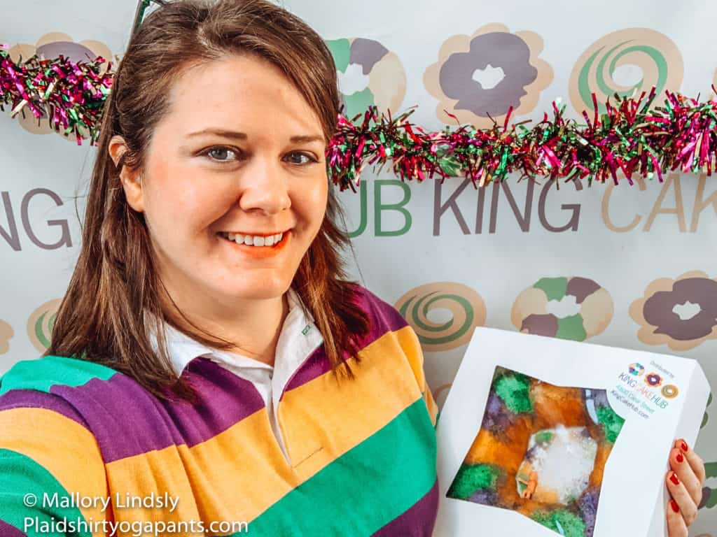 Do you want to learn how to Ship King Cakes from New Orleans or find the best King Cake Flavors then read more. Mallory posing with a King Cake at the selfie wall at the King Cake Hub where you can find some of the best king cake new orleans
